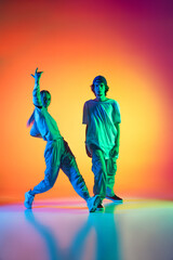 Two dancers, young girl and boy dancing hip-hop in casual sports youth clothes on gradient multi...