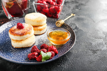 Plate with tasty cottage cheese pancakes, raspberry and honey on dark background