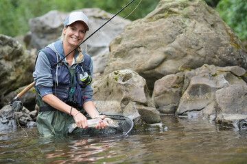 young woman fly fishing in a mountain river - 457277478