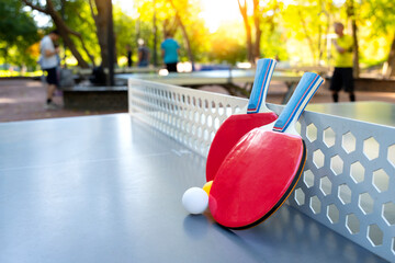 Street table tennis. Two tennis rackets with balls are on the ping pong table.