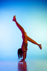 Obraz premium Young sportive girl dancing break dance alone isolated on colorful background at dance hall in neon light. Youth culture, movement, style and fashion, action.