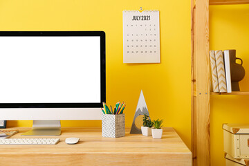 Modern workplace with computer and decor near color wall