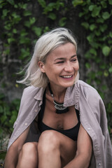 Close-up portrait of laughing pretty caucasian young woman with blond hair, wearing casual clothing and stylish necklace. Beautiful smile 