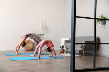 Little girl with her mother practicing yoga at home © Pixel-Shot