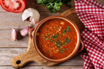 Red lentil soup in bowl on rustic wooden table. Top view