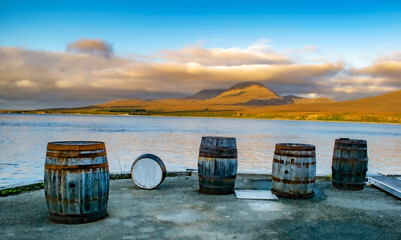 Casks and Barrels in a Whiskey distillery Islay in Scotland coast with Jura behind casks and...
