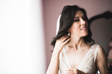 Fototapeta premium Beautiful bride wearing fashion wedding dress with feathers with luxury delight make-up and hairstyle, studio indoor photo shoot
