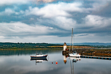 Lighthouse in Lochgilphead Scotland reflected on the water Old lighthouse and boats sunset reflected on the water Mirror mirroing Loch lake