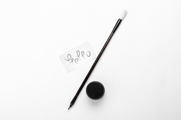 Paper with word HELLO, brush and ink on white background