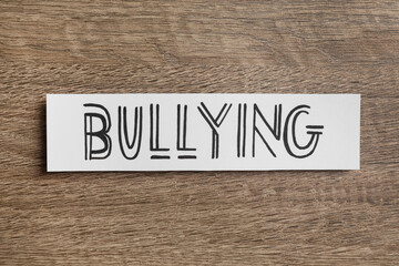 Fototapeta premium Paper card with word Bullying on wooden table, top view