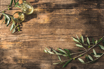 Rustic wooden olive background with olive oil and olive branches, sunlight for graphic design and text, copy space, flat lay