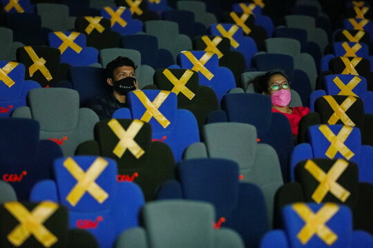Visitors wearing protective masks watch a movie at a cinema as it is reopened after the ease of restrictions amid the coronavirus disease (COVID-19) pandemic in Jakarta