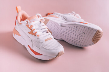 White women's sneakers with coral inserts, on pink background