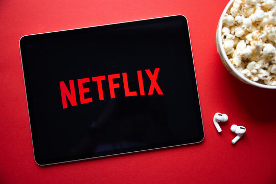 Riga, Latvia - April 14, 2021: Netflix logo on iPad with popcorn and wireless earbuds.