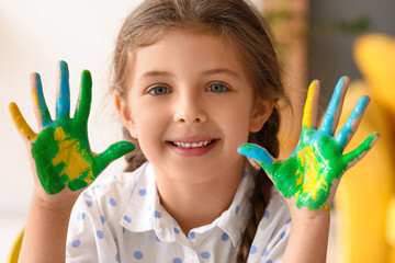 Cute little girl with hands in paint at home, closeup