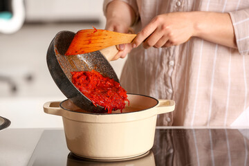 Woman adding frying beet to cooking pot, closeup