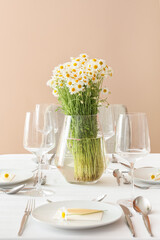 Stylish table setting and chamomile flowers in dining room