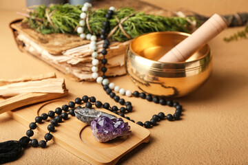 Composition with Tibetan singing bowl, gemstones, beads and Palo Santo on color background