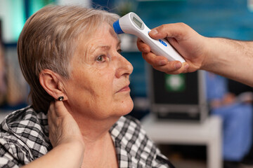 Close-up of assistant man helper checking temperature using medical infrared thermometer discussing...