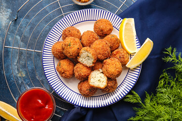Plate with tasty cod cutlets and sauce on color background