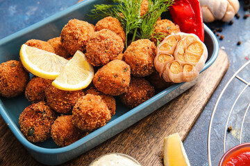 Baking dish with tasty cod cutlets and spices on color background, closeup