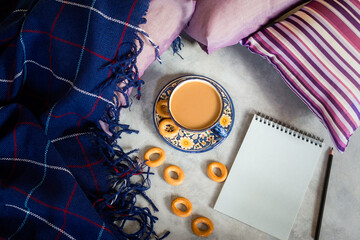 Autumn composition. Coffee notepad plaid top view flat lay. The concept of comfort, autumn winter cold. A mockup for writing, a white sheet of a notebook. Cozy still life with a blue blanket, pillows