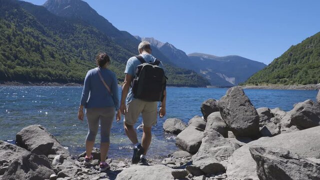 Tourist couple close to the lake in Spanish Pyrenees Mountain in a sunny day..
