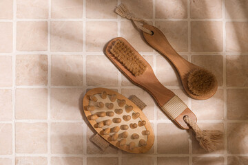 Different massage brushes on light tile background
