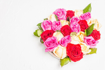 Composition of fresh multicolored roses on ceramic stand