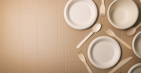 Obraz na płótnie Canvas eco friendly disposable tableware. paper dishes and wooden cutlery on cardboard background. copy space