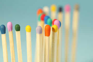 Matches with colorful heads on light blue background, closeup
