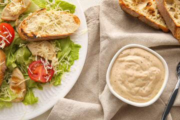 Plate of tasty Caesar salad and sauce on table, closeup