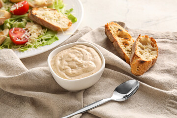 Bowl of tasty Caesar sauce and croutons on table
