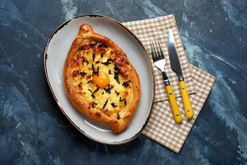 Plate with tasty Ajarian khachapuri on color background