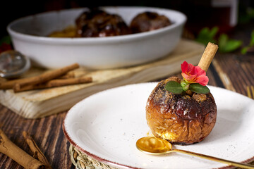 roasted red apples with cinnamon and honey in white earthenware dish on dark wooden table