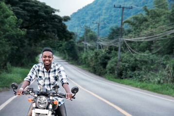 African biker man in the helmet riding a motorcycle rides on highway road