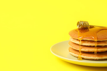 Plate of tasty pancakes with honey on color background, closeup