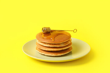 Plate of tasty pancakes with honey on color background