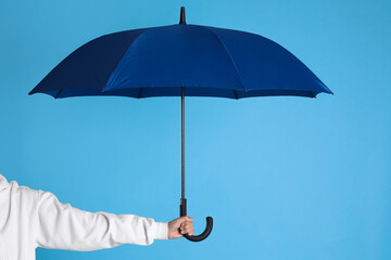 Woman with open bright umbrella on light blue background, closeup