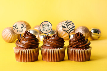 Tasty cupcakes for New Year 2022 celebration on color background