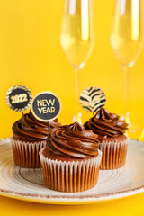 Plate with tasty cupcakes for New Year 2022 celebration on color background