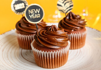 Plate with tasty cupcakes for New Year 2022 celebration on color background, closeup