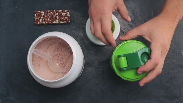 Process of making chocolate powder whey protein drink with milk in a shaker, slow motion, top view