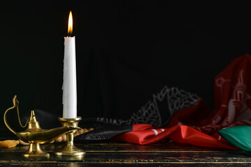 Burning candle, lamp and flag of Afghanistan on table against dark background