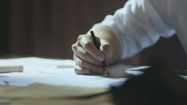 closeup shot of designer's hand sketching on paper when thinking indoors
