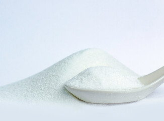Image close-up isolated sugar-white granulated crystal and heap on white background with spoon...