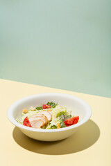 Caesar salad in white plate on yellow hard shadow modern