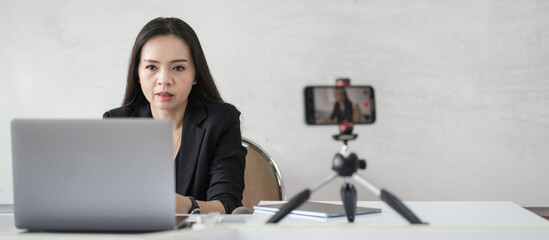 Adult Asian female college teacher teaching online via video conference meeting to students at...