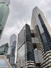 Obraz premium Facade of modern skyscraper with glass walls. From below of contemporary tall skyscraper with glass walls against cloudy sky in downtown