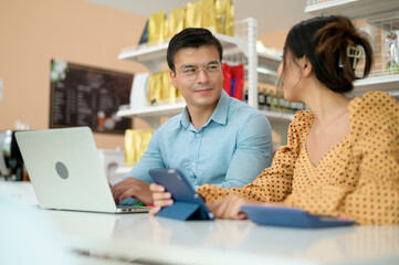 Business owners are analyzing business data , talking and smiling in modern shop